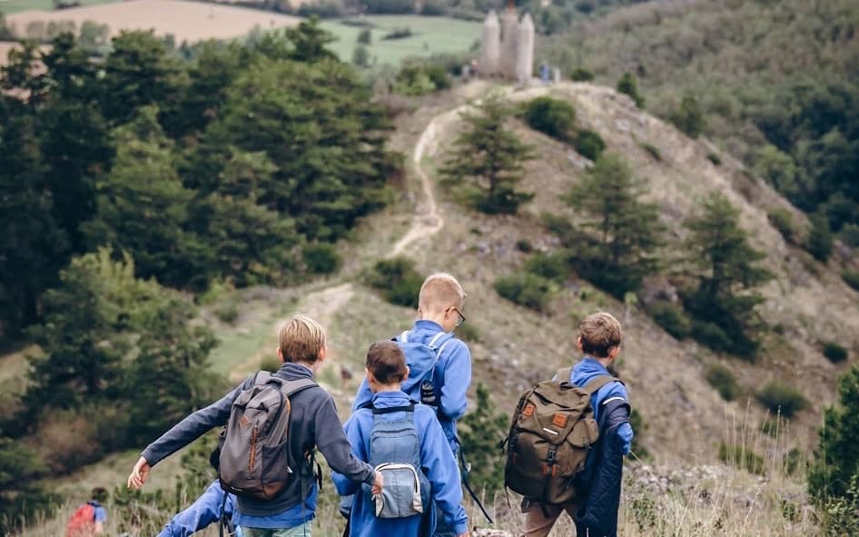 Collégiens en randonnée sur un sentier de crête, une tour au loin
